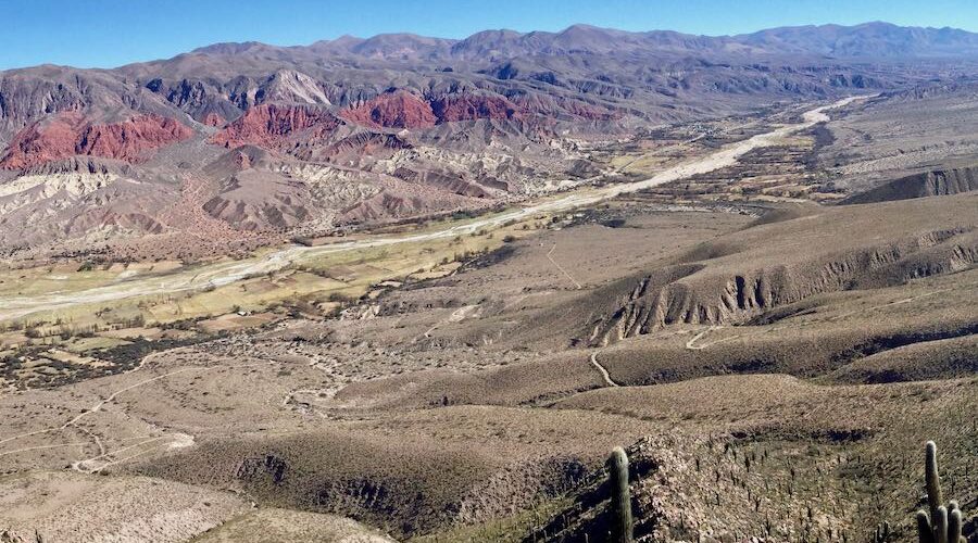 View of the Quebrada de Humahuaca from the path leading to Argentina’s highest vineyard, Moya Vineyard. Features a dry riverbed, centennial cacti, and a panoramic view of the valley stretching towards Bolivia, captured during a Wine Tours in Style experience.