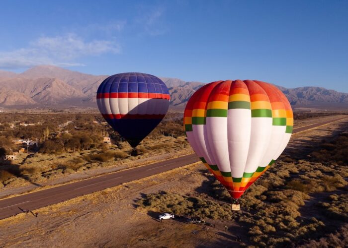 Hot air balloons soaring above the vineyards and desert landscape of Cafayate, Salta, with the Andes Mountains in the background — a luxury wine tour experience in Northern Argentina.
